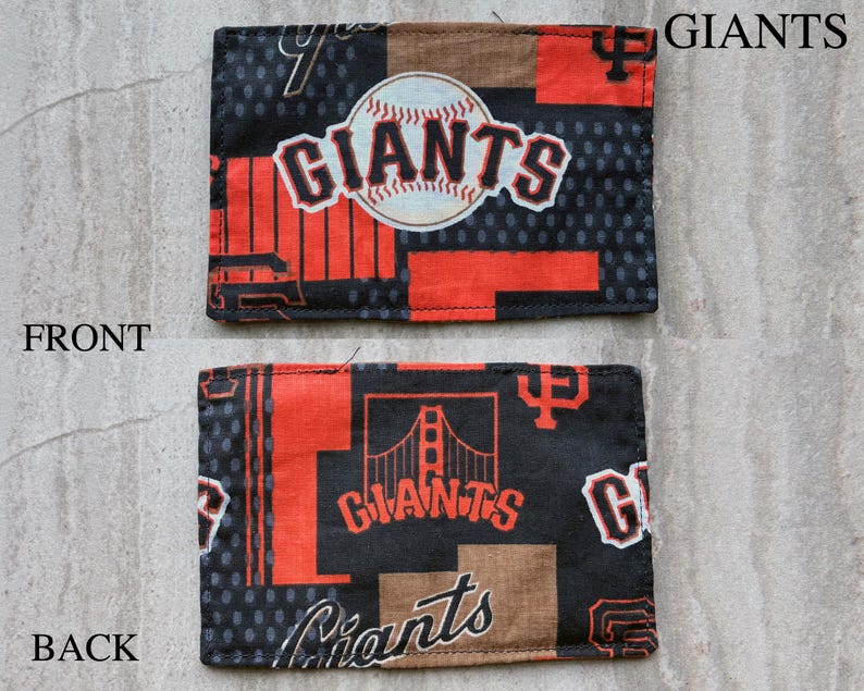 May include: A rectangular fabric patch featuring the San Francisco Giants baseball team logo. The front displays a baseball graphic with the word GIANTS, while the back shows a Golden Gate Bridge illustration and the word GIANTS in orange and black.