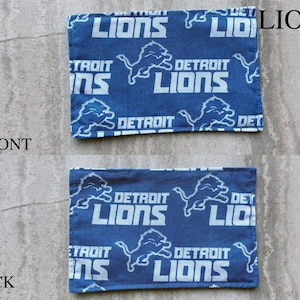 May include: A rectangular fabric patch featuring a repeating pattern of the Detroit Lions logo and text in white on a blue background. The image displays both the front and back sides of the fabric, each labeled with text indicating its orientation.