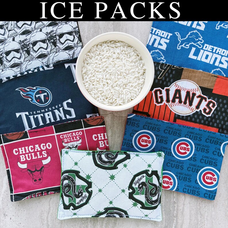 May include: A collection of rectangular fabric ice packs featuring various sports team logos and character prints, including Tennessee Titans, Chicago Bulls, Detroit Lions, San Francisco Giants, and Chicago Cubs, surrounding a bowl of white rice.
