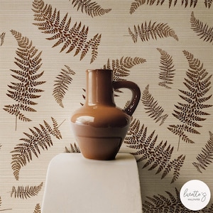 May include: A brown ceramic vase with a handle sits on a white surface, against a backdrop of wallpaper featuring a repeating fern pattern in shades of brown. The wallpaper has a subtle striped texture.
