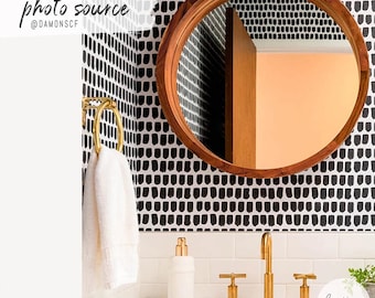 May include: A bathroom interior with a circular wooden mirror, gold taps, and a white sink. The wall has a black and white pattern. A white towel hangs on a gold towel ring. The image includes the text "photo source @DAMONSFC".