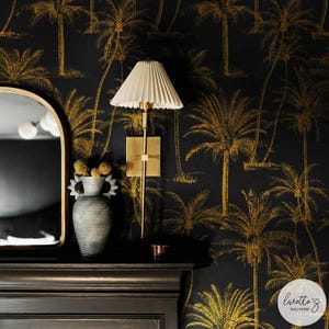 May include: Black wallpaper with a gold palm tree pattern. A black and gold lamp with a white shade is mounted on the wall. A grey ceramic vase with dried flowers sits on a black mantel.