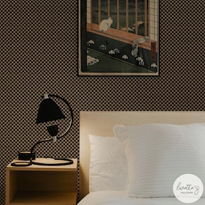 May include: A bedroom scene with black and brown chequered wallpaper. A black desk lamp sits on a wooden bedside table next to a bed with white pillows and a headboard. A framed artwork hangs above the bed.