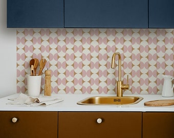 May include: A kitchen backsplash with a geometric pattern of pink and beige semi-circles. The backsplash is behind a gold kitchen sink with a gold faucet.
