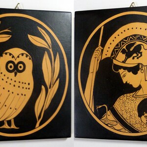 Könnte beinhalten: Zwei quadratische Wandkunstwerke mit schwarzen Hintergründen und goldfarbenen Illustrationen. Eines zeigt eine Eule in einem kreisförmigen Rahmen aus Blättern. Das andere zeigt eine Figur in Helm und Rüstung, ebenfalls in einem Kreis.