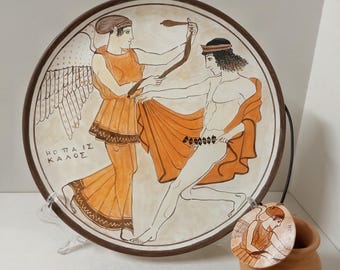 Hand-decorated pendant and plate featuring Nike (Victory), a figure taken from ancient Greek pottery.