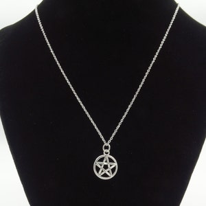 May include: A silver chain necklace with a silver pendant featuring a five-pointed star.