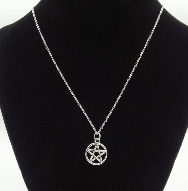 May include: A silver chain necklace with a silver pendant featuring a five-pointed star.