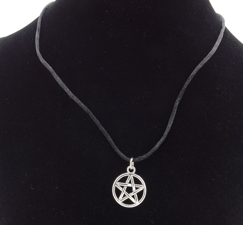 May include: A silver pentagram pendant necklace on a black cord.