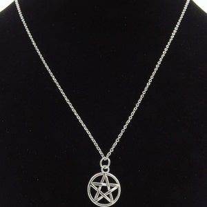 May include: A silver chain necklace with a silver pendant featuring a five-pointed star in a circle.