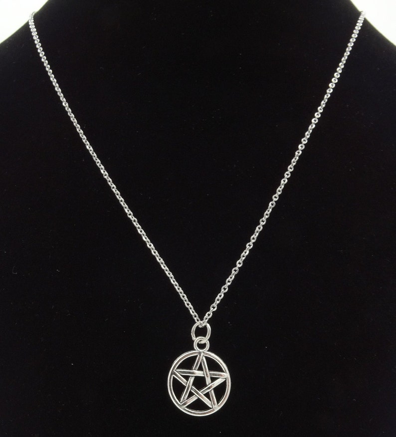 May include: A silver chain necklace with a silver pendant featuring a five-pointed star in a circle.