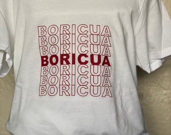 May include: White t-shirt with the word "BORICUA" repeated in red lettering, stacked on top of each other.