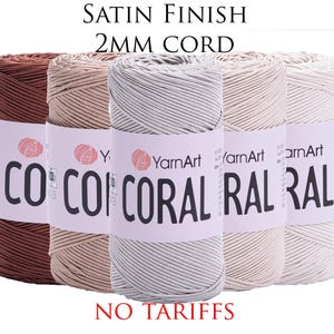 May include: Five spools of YarnArt Coral satin finish 2mm cord in shades of brown, beige, light grey, off-white, and white. Each spool has a label with the brand name and the word "CORAL". The text "NO TARIFFS" is at the bottom.