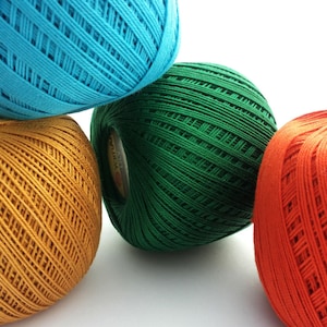 May include: Four balls of yarn in different colors: turquoise, green, orange, and yellow. The yarn is textured and has a woven appearance.