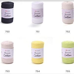 May include: A collection of six spools of YarnArt Macrame Cotton yarn in various colors. The colors include navy, white, beige, light beige, yellow, and light green. Each spool has a label with the brand name and product type.