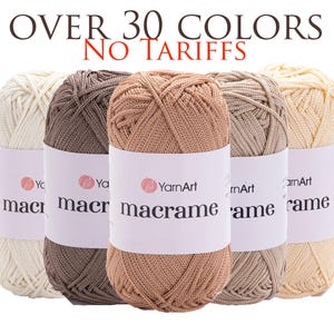 Könnte beinhalten: Fünf Stränge YarnArt Makramee-Garn in verschiedenen neutralen Farben, darunter Creme, Braun und Beige. Das Bild zeigt den Text "OVER 30 COLORS" und "NO TARIFFS". Jeder Strang hat ein weißes Etikett mit dem Markennamen.