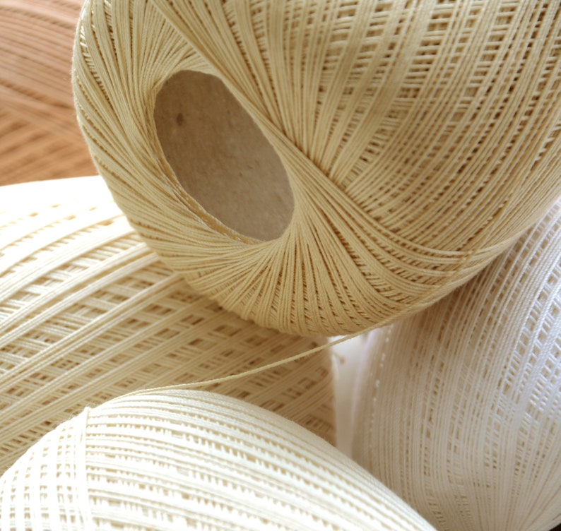 May include: Three balls of white yarn, each with a different weave pattern. The yarn is soft and fluffy, and the balls are arranged in a pile.
