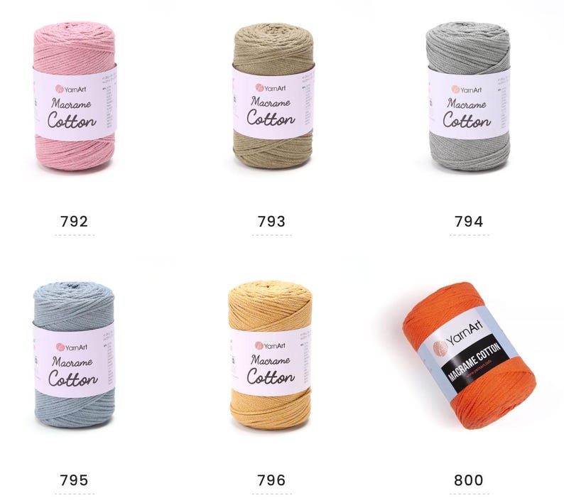 May include: A collection of six spools of YarnArt Macrame Cotton yarn in various colors. The colors include pink, olive green, gray, blue, yellow, and orange. Each spool has a label with the brand name and product details.