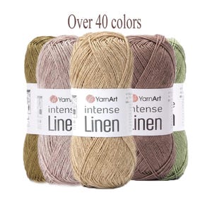 Può includere: Cinque gomitoli di filato YarnArt Intense Linen in varie tonalità terra tra cui beige, malva e verde oliva. Ogni gomitolo presenta un'etichetta di carta bianca con il testo YarnArt intense Linen e icone. L'immagine include il testo Over 40 colors.