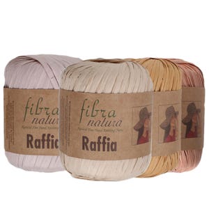 Peut inclure: Quatre bobines cylindriques de fil Fibra Natura Raffia dans des tons variés de rose clair, beige, ocre et vieux rose. Chaque bobine porte une étiquette en papier brun avec le texte Fibra Natura Raffia et l'illustration d'une personne en chapeau.