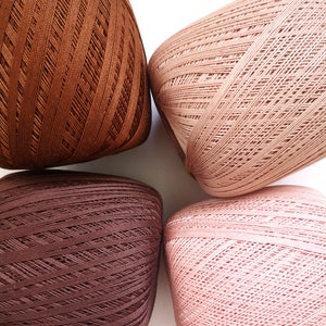 May include: Four balls of yarn in different shades of brown. The yarn is a soft, textured material and is perfect for knitting or crocheting.