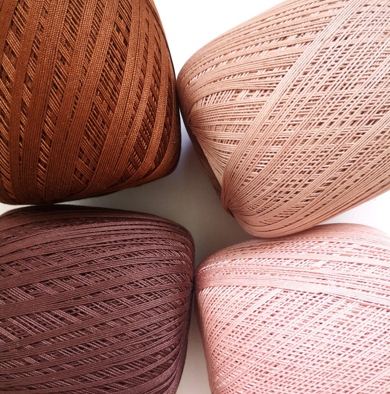 May include: Four balls of yarn in different shades of brown. The yarn is a soft, textured material and is perfect for knitting or crocheting.