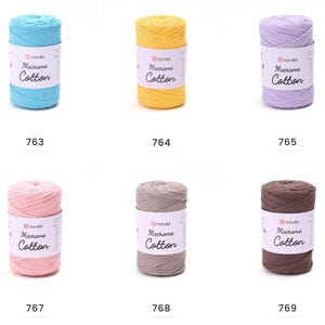 May include: A collection of six spools of YarnArt Macrame Cotton yarn in various colors. The colors include light blue, yellow, lavender, pink, gray, and brown. Each spool has a white label with the brand name and product details.