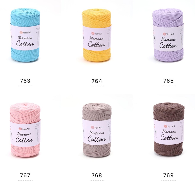 May include: A collection of six spools of YarnArt Macrame Cotton yarn in various colors. The colors include light blue, yellow, lavender, pink, gray, and brown. Each spool has a white label with the brand name and product details.