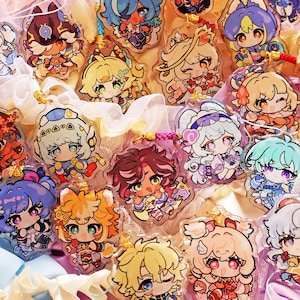 May include: A collection of twenty-one clear acrylic charms featuring colorful chibi-style anime characters. Each charm is attached to a small, decorative cord loop. The characters display various hair colors, outfits, and expressions in a flat design.