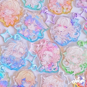 Puede incluir: Una colección de coloridos colgantes acrílicos de estilo anime con varios personajes. Cada colgante tiene un diseño único con colores pastel, sujeto a un llavero en forma de estrella o circular. Los colgantes son de color rosa, azul, verde y amarillo.