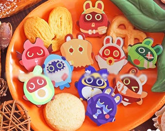 May include: An orange plate holds an assortment of colorful, cartoon animal-shaped magnets. The magnets feature various designs, including rabbits, bears, and other creatures. A cookie and pastries are also on the plate.