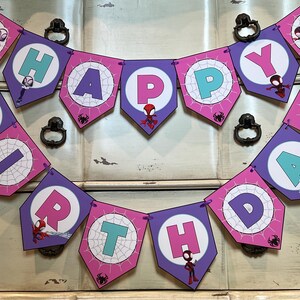May include: A Happy Birthday banner featuring purple and pink pentagonal pennants with spiderweb patterns. Each pennant displays a letter in teal or pink, accented with small cartoon spider characters and web motifs throughout the design.
