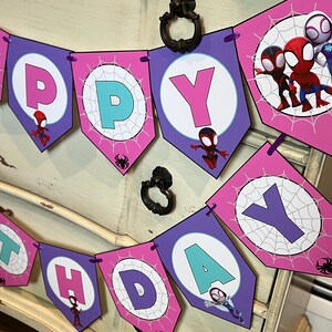 May include: A decorative banner spelling HAPPY BIRTHDAY with purple and pink pentagonal flags. Each flag features a white circle with a spiderweb pattern, a letter, and cartoon character illustrations of Spider-Man, Miles Morales, and Ghost-Spider.