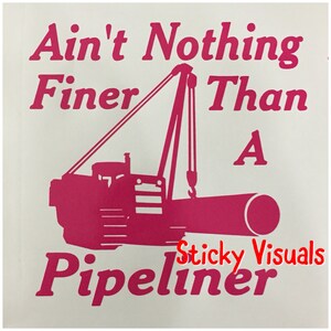 May include: Pink silhouette of a construction vehicle with a crane lifting a pipe. The text "Ain't Nothing Finer Than A Pipeliner" is written above the vehicle. The text "Sticky Visuals" is written below the vehicle.
