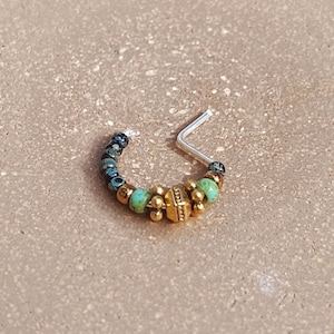 22ゲージのスターリングシルバーワイヤーに金または銀メッキのピューターで作られた緑がかったターコイズ色のガラスビーズが付いたノーズリング。Lポスト付き。