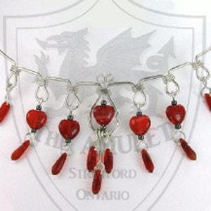 May include: Silver necklace with a delicate design and multiple dangling red heart-shaped beads.