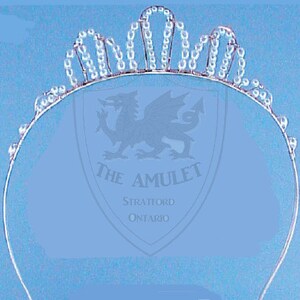 May include: A silver tiara with a delicate design of small, clear crystals. The tiara is made of metal and has a rounded shape.