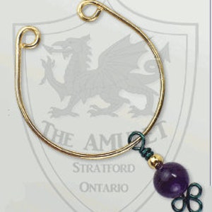 May include: A gold-toned nose ring with a purple amethyst bead hanging from it.