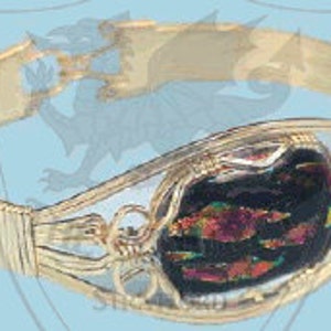 May include: Gold-toned bangle bracelet with a black and iridescent glass stone set in a filigree design.