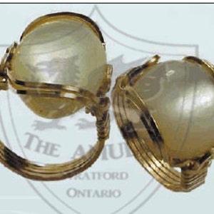 May include: Two gold rings with a white, round, iridescent stone set in each. The rings are made of twisted wire.