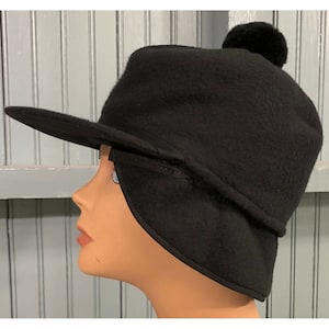 May include: Black fleece hat with a pom pom on top and a fold-down ear flap. The hat has a brim that can be worn up or down.