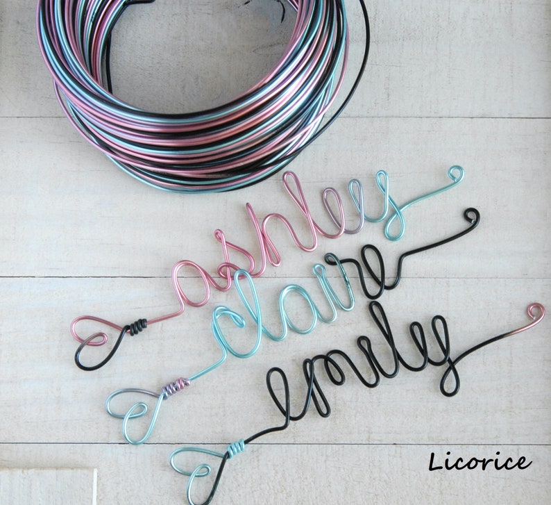 May include: A coil of multi-colored wire in black, pink, and light blue, alongside three wire-formed names: ashley in pink, claire in light blue, and emily in black. Each name features a small heart-shaped loop at the end. The text Licorice is visible.