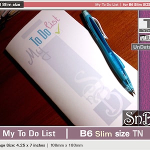 Puede incluir: Una libreta blanca con las palabras "My To Do List" escritas en azul y rosa. La libreta es de tamaño B6 Slim y tiene un bolígrafo azul encima. La libreta está sobre una superficie de madera. El texto "My To Do List | B6 Slim size TN" está en la parte inferior de la imagen. El texto "Page Size: 4.25 x 7 inches | 108mm x 180mm" está en la parte inferior de la imagen.