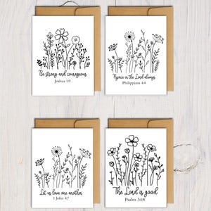 May include: Four white greeting cards with black floral line art designs and inspirational quotes. Each card is paired with a brown envelope. The quotes include "Be strong and courageous," "Rejoice in the Lord always," "Let us love one another," and "The Lord is good."