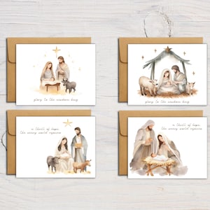 May include: Set of four Christmas cards featuring watercolor illustrations of the Nativity scene. The cards feature a brown background with gold accents and the text "glory to the newborn king" and "a thrill of hope, the weary world rejoices".