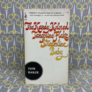May include: A vintage paperback book cover with the title "The Kandy-Kolored Tangerine-Flake Streamline Baby" by Tom Wolfe. The title is in a colorful, stylized font.