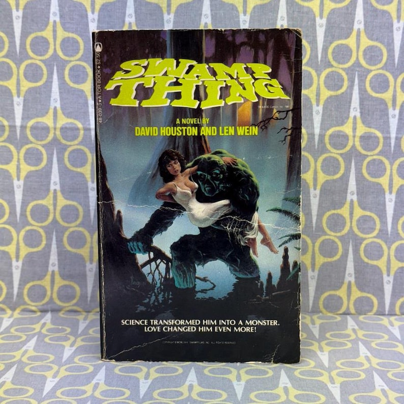 May include: Vintage paperback book titled "Swamp Thing" by David Houston and Len Wein. The cover art depicts a green monster carrying a woman in a white dress. The text reads, "Science transformed him into a monster. Love changed him even more!"