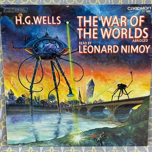 May include: A vintage record album cover featuring a dramatic illustration of a Martian tripod attacking a city. The album is titled "The War of the Worlds" by H.G. Wells, read by Leonard Nimoy, and is abridged. The cover is a vibrant orange, yellow, and red sunset with a dark blue sky.
