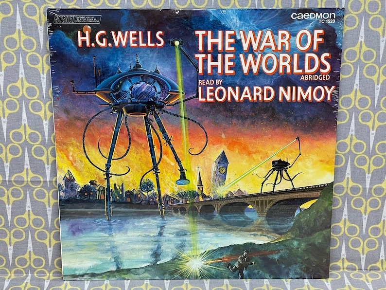 May include: A vintage record album cover featuring a dramatic illustration of a Martian tripod attacking a city. The album is titled "The War of the Worlds" by H.G. Wells, read by Leonard Nimoy, and is abridged. The cover is a vibrant orange, yellow, and red sunset with a dark blue sky.