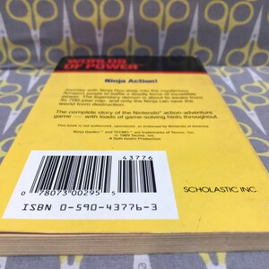 May include: Yellow and black back cover of a book titled "Worlds of Power: Ninja Action!" with a barcode and ISBN number. The book is published by Scholastic Inc.